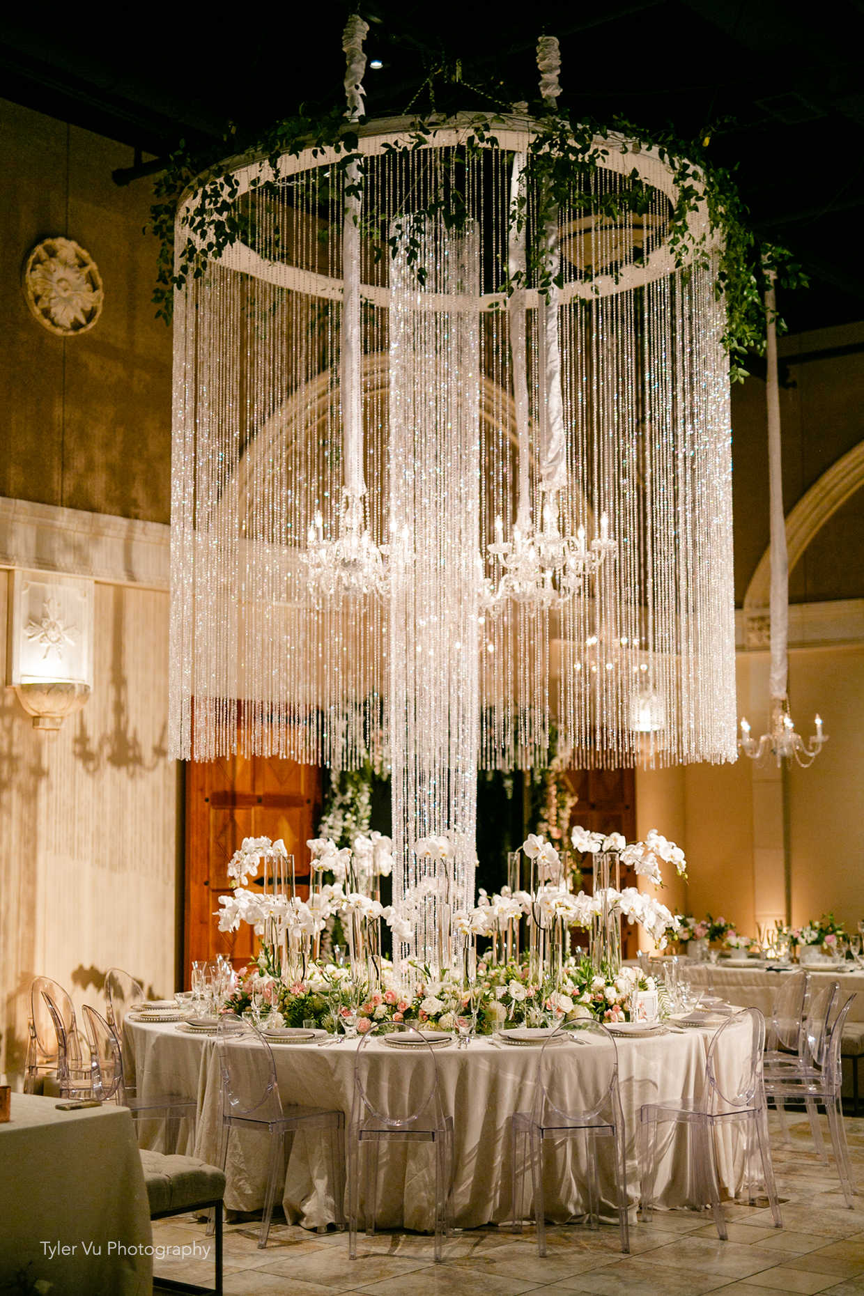 Stunning wedding reception table with overhead chandelier and orchid centerpieces at Casa Real at Ruby Hill Winery (www.casarealevents.com).  Photo by: Tyler Vu Photography; Florals and Design: Nicole Ha Design; Lighting: Fantasy Sound Event Services; Chairs: Pleasanton Rentals
